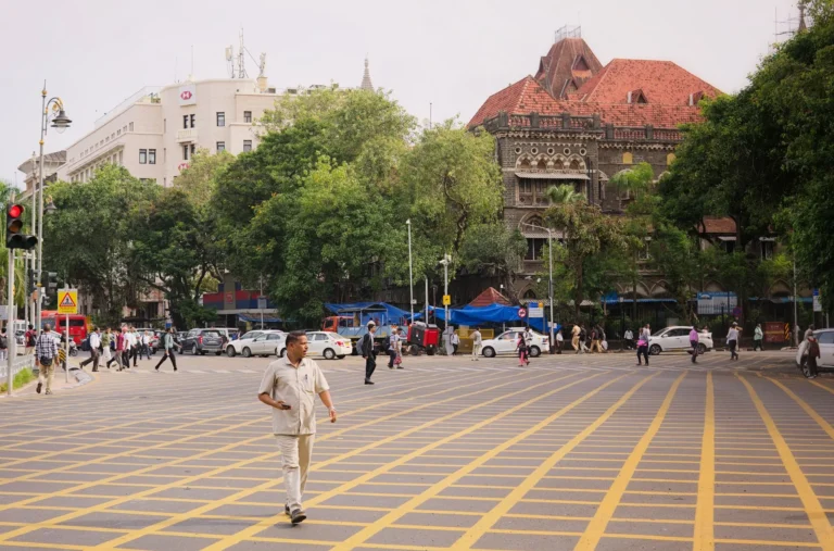A vibrant street scene in Mumbai with people crossing and historic architecture.