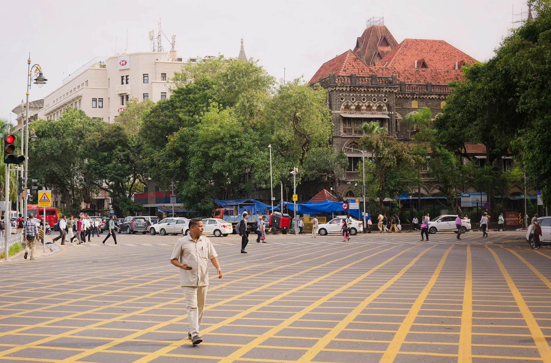 A vibrant street scene in Mumbai with people crossing and historic architecture.
