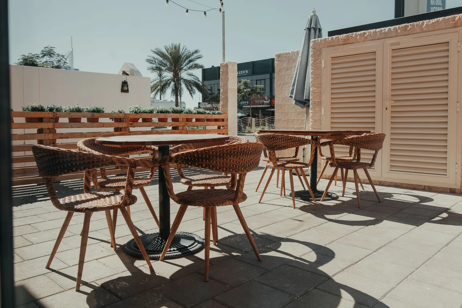 Cozy outdoor cafe seating in Dubai with wicker chairs and palm tree view.