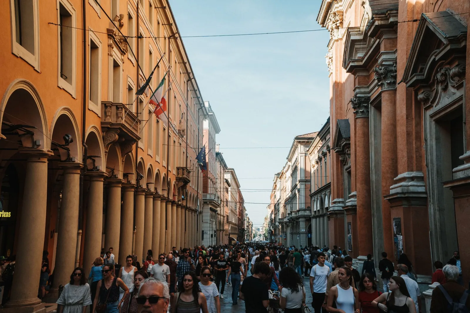 A vibrant urban scene in Bologna, Italy, showcasing historic architecture and a lively crowd.