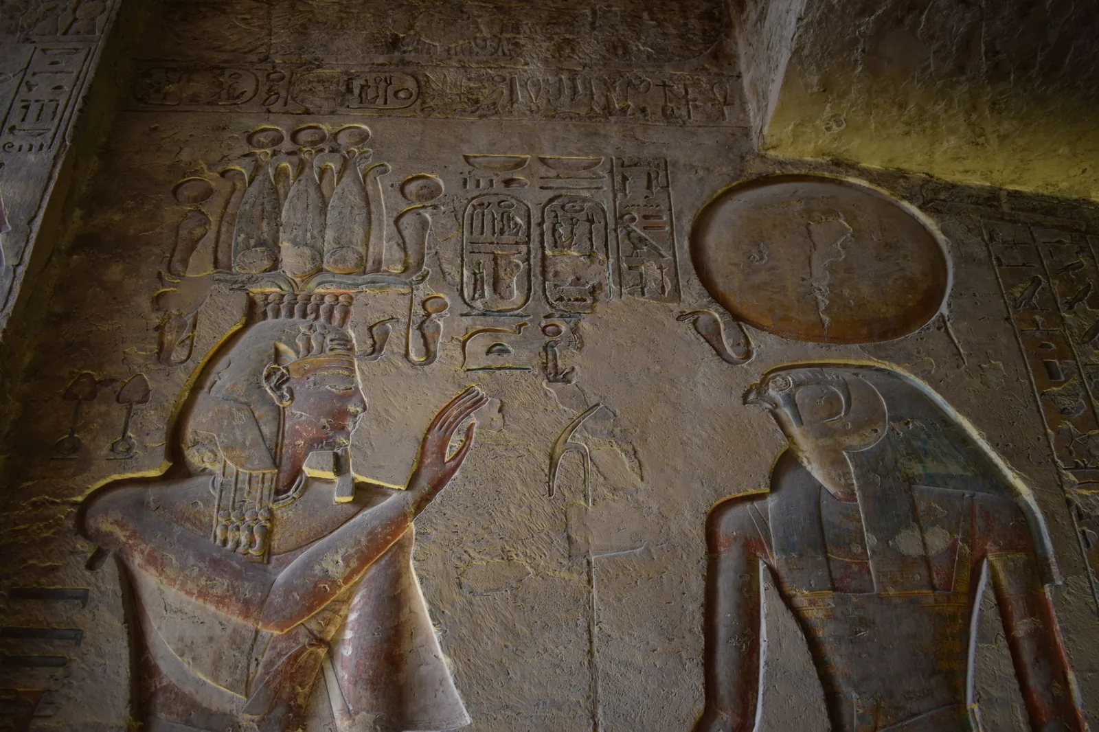 Detailed ancient Egyptian relief carvings of gods in a historic temple setting.