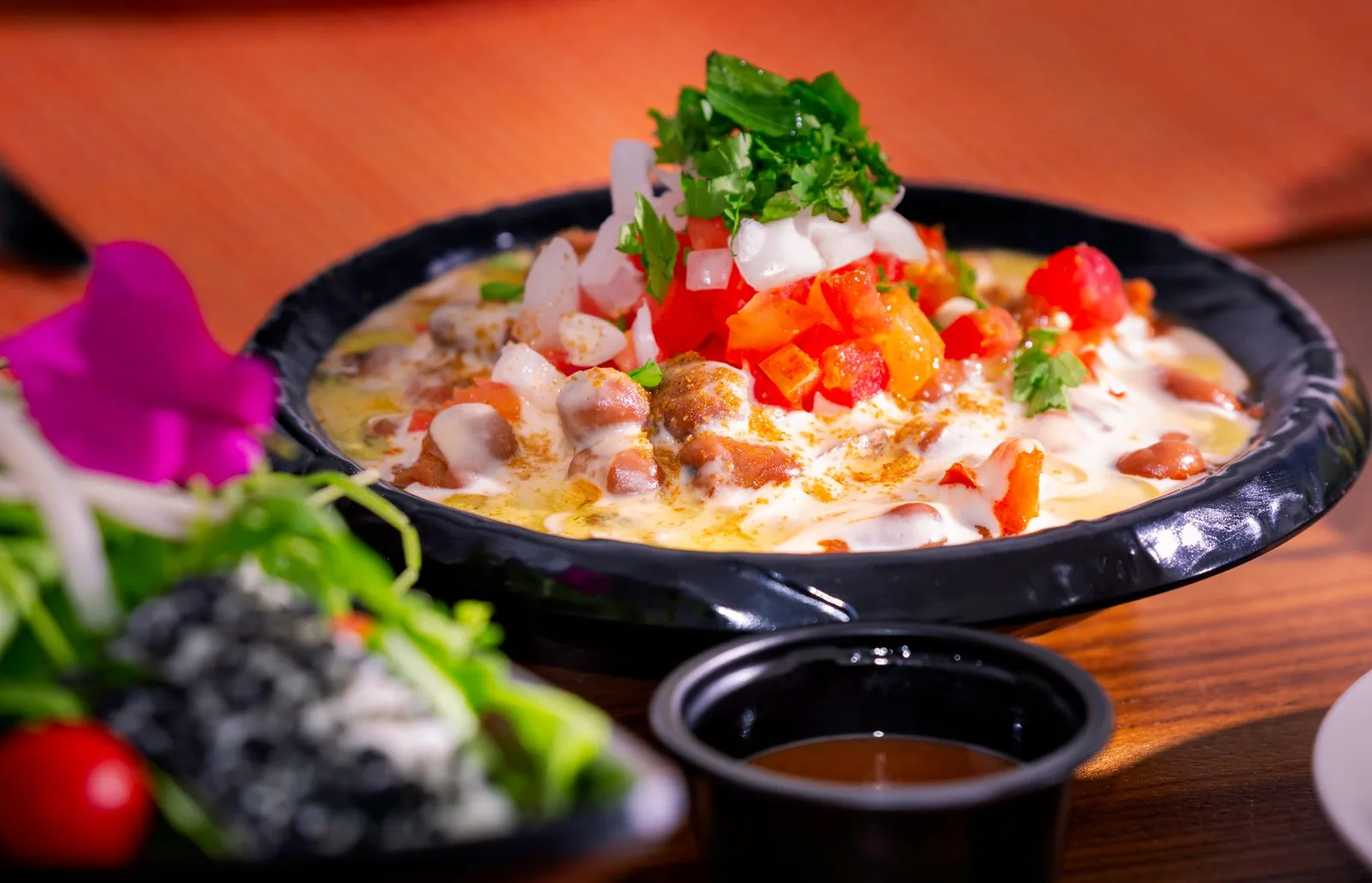Vibrant Mexican dish with beans, cheese, and fresh herbs in an artistic presentation.