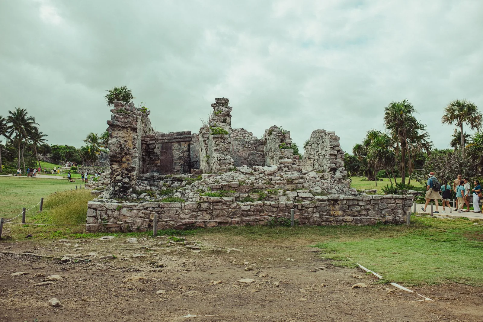 Explore the ancient Mayan ruins in Tulum, Mexico, set against lush greenery and a cloudy sky.