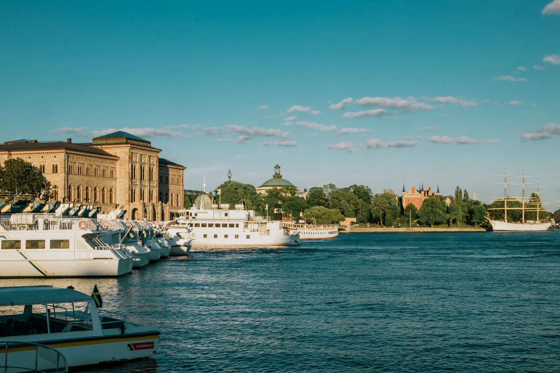 Beautiful summer view of Stockholm's waterfront with boats and historic buildings under a clear sky.