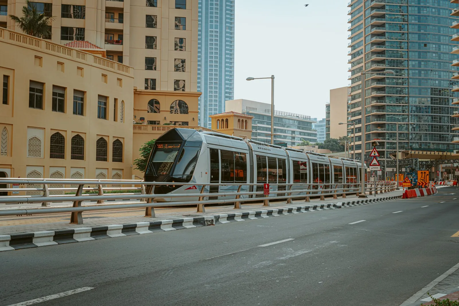 View of a sleek tram passing through downtown Dubai, showcasing the blend of traditional and modern architecture.