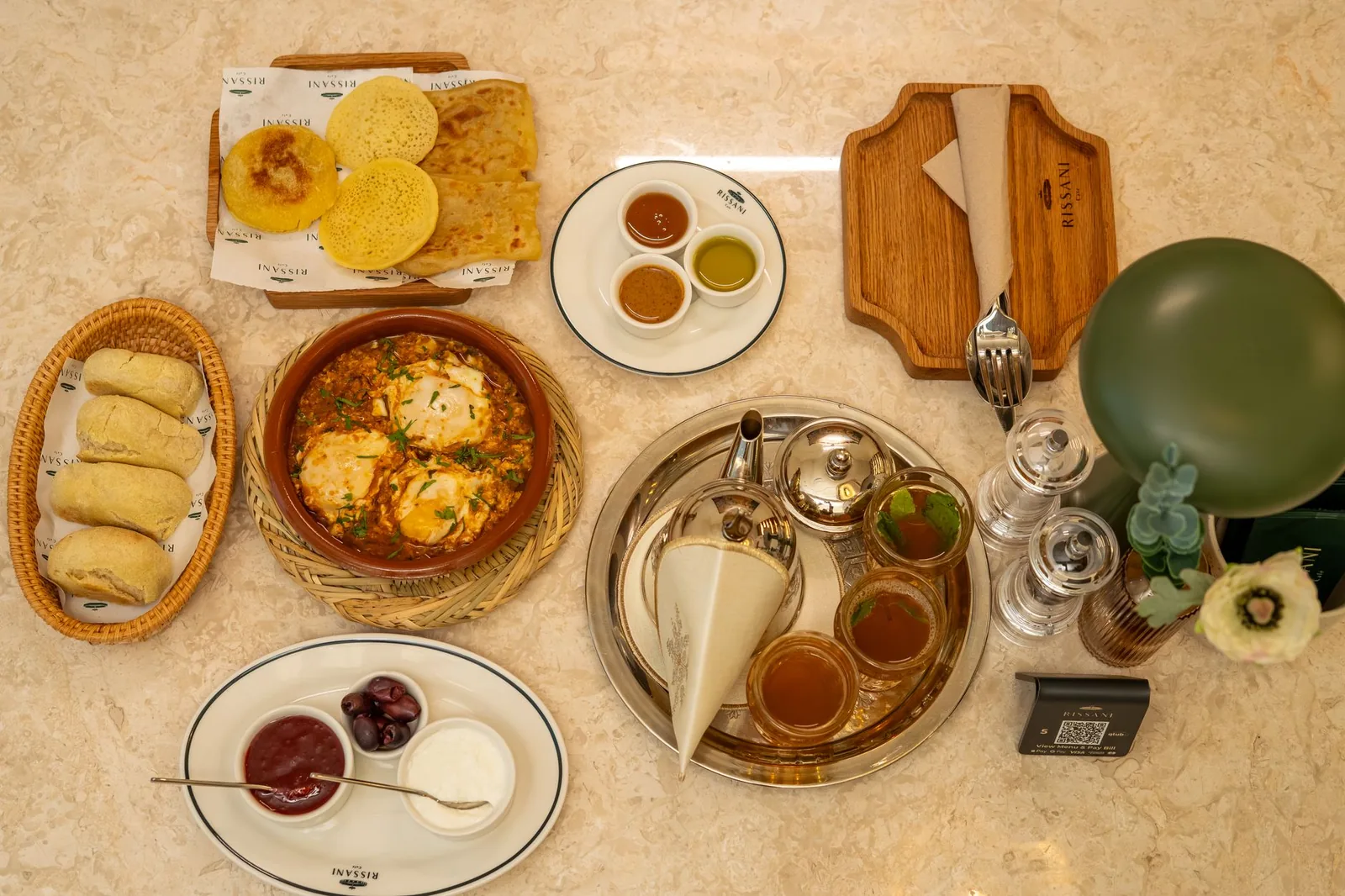 A delicious Arabian breakfast spread with bread, eggs, dips, tea, and condiments, top view.