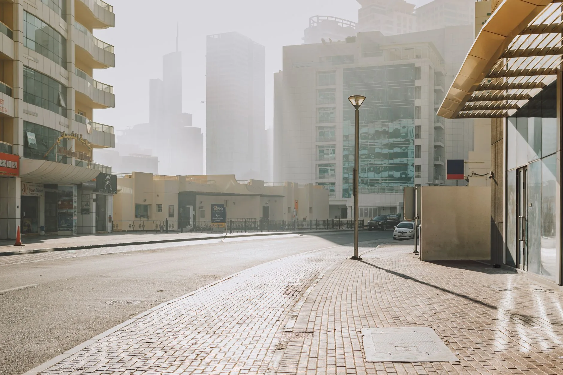 A quiet, sunlit street in downtown Dubai showcasing modern architecture.