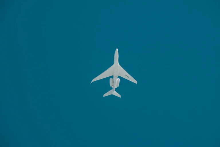 A commercial jet captured mid-flight against a deep blue sky in Dubai.