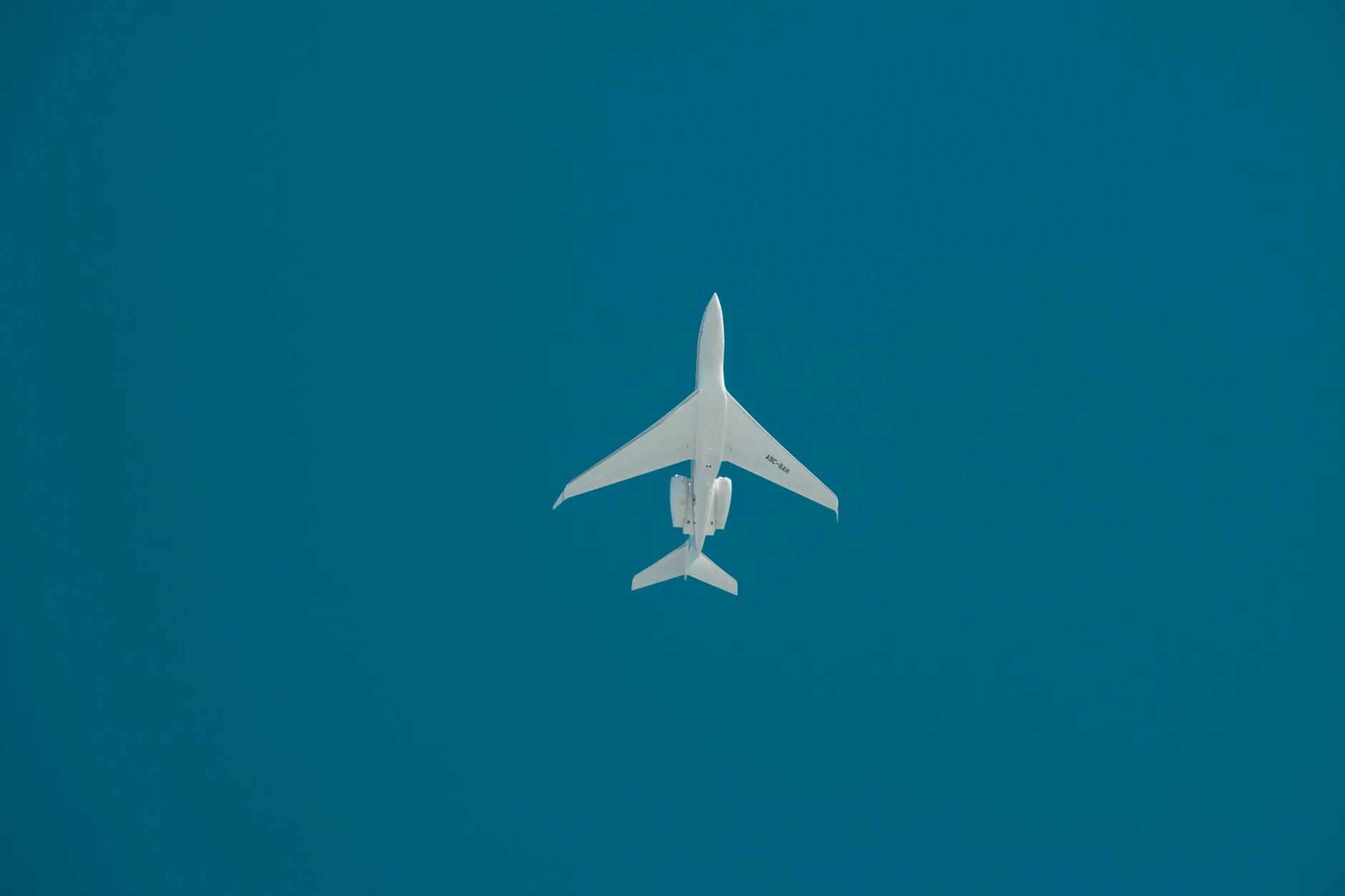 A commercial jet captured mid-flight against a deep blue sky in Dubai.