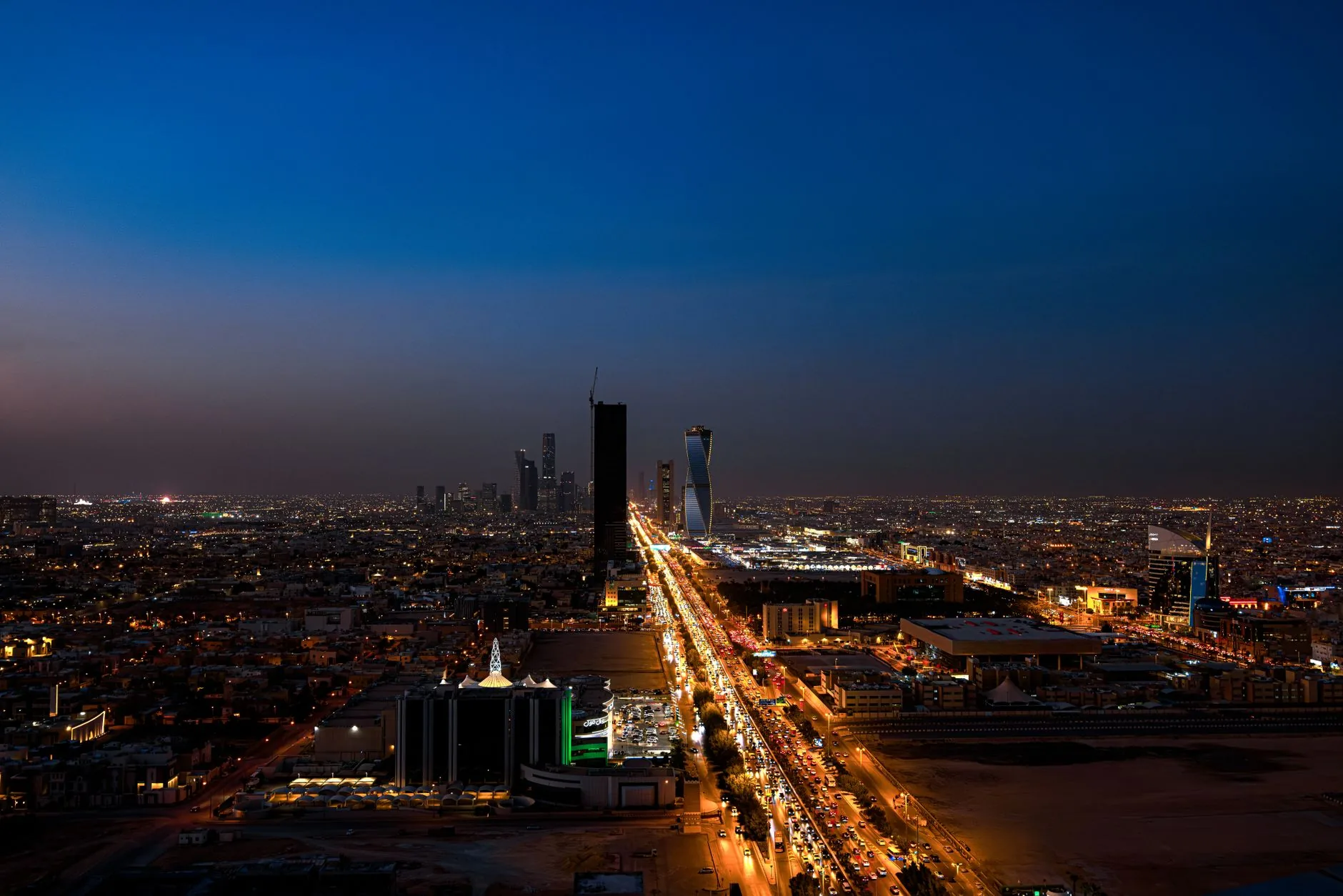Dramatic aerial twilight view of Riyadh city skyline with lit streets.