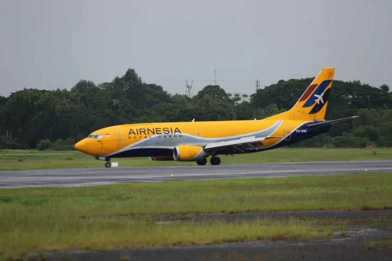 Airnesis cargo airplane taxiing on the runway of Jakarta airport with lush greenery in the background.