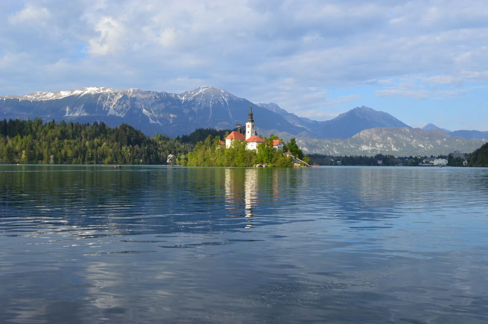 Stunning view of Lake Bled, Slovenia with a picturesque church and snow-capped mountains in the background.