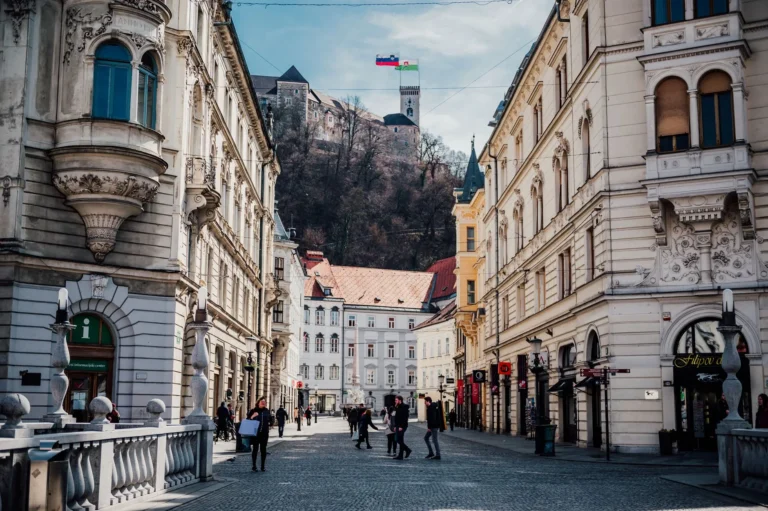 Stroll through a historic street in Ljubljana, Slovenia, with a view of the castle atop the hill.