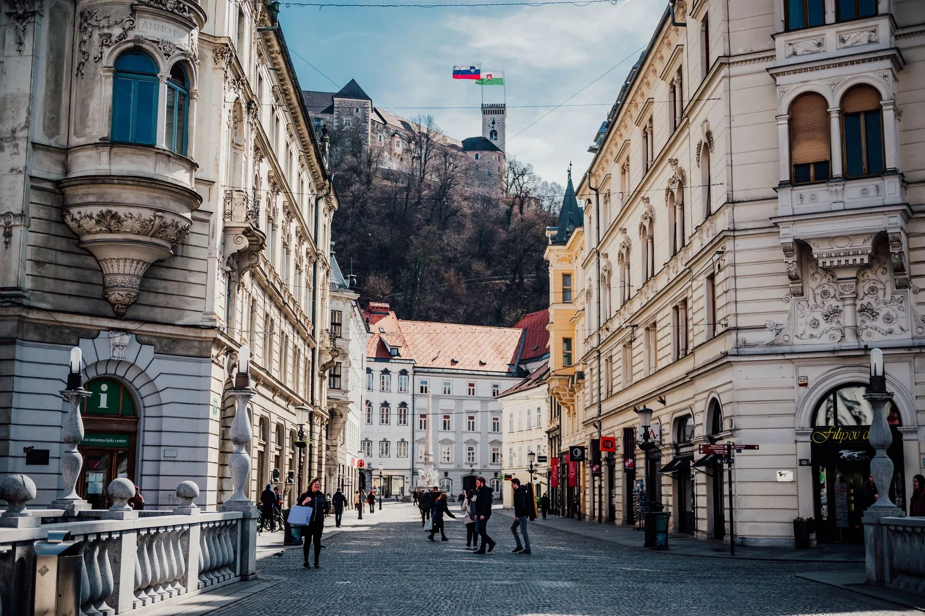 Stroll through a historic street in Ljubljana, Slovenia, with a view of the castle atop the hill.