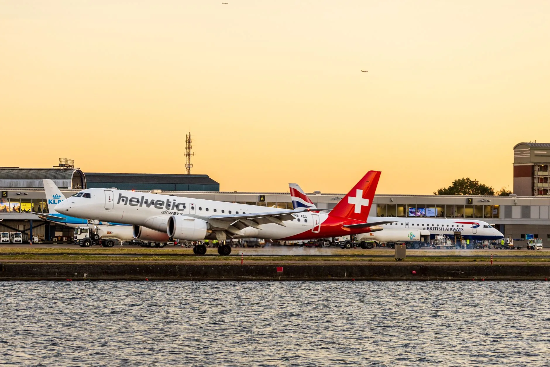 Helvetic Airways airplane on the runway at London City Airport during a vibrant sunset.