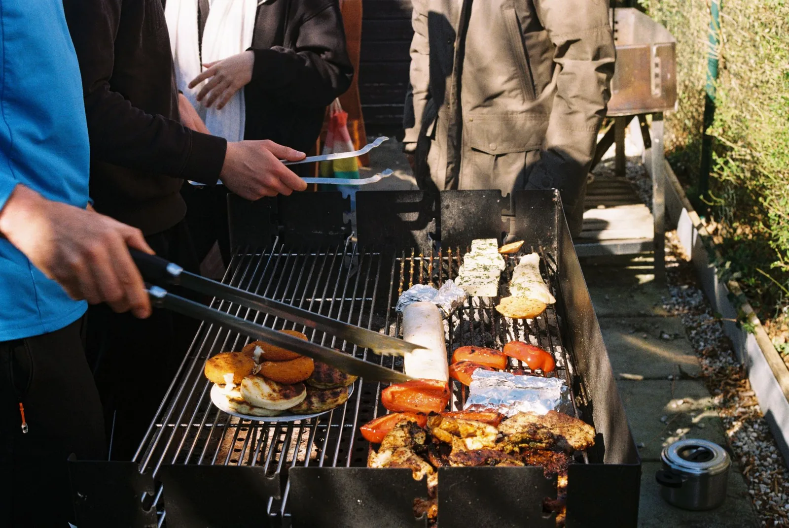 Men grilling assorted food at an outdoor barbecue event in Munich, Bavaria, Germany.