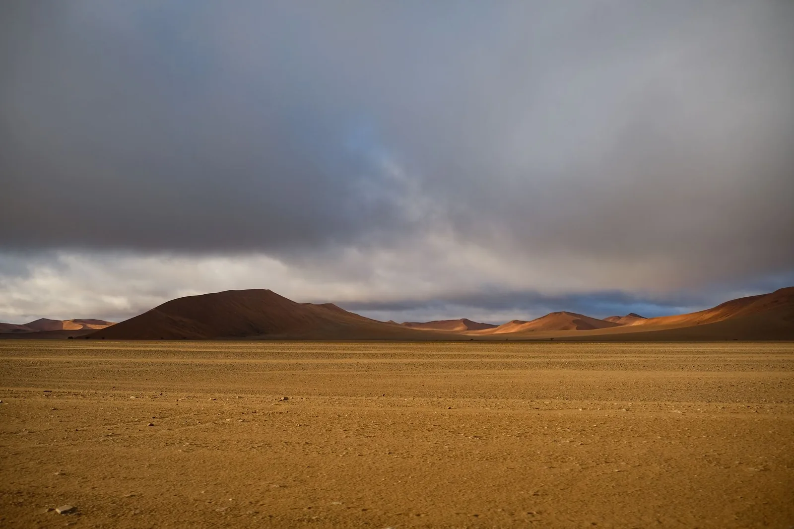 Scenic view of Namibia's Namib Desert featuring vast sand dunes and a dramatic sky.