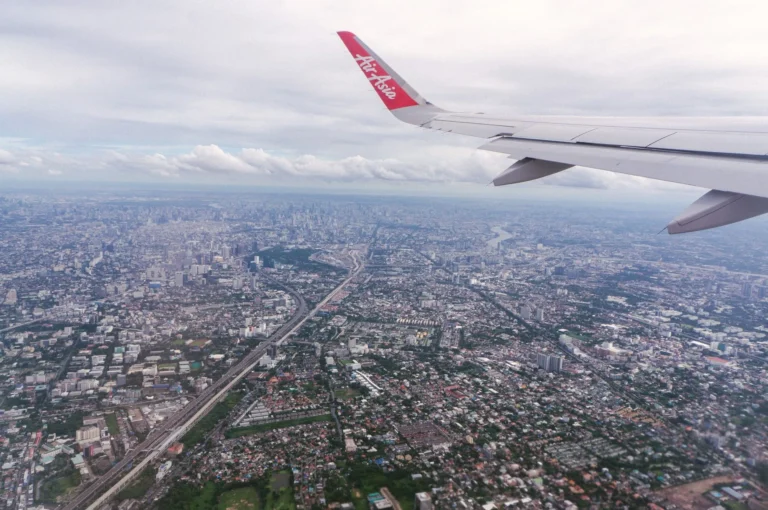 Scenic aerial view of Bangkok cityscape from an airplane window at daytime, showcasing urban sprawl.