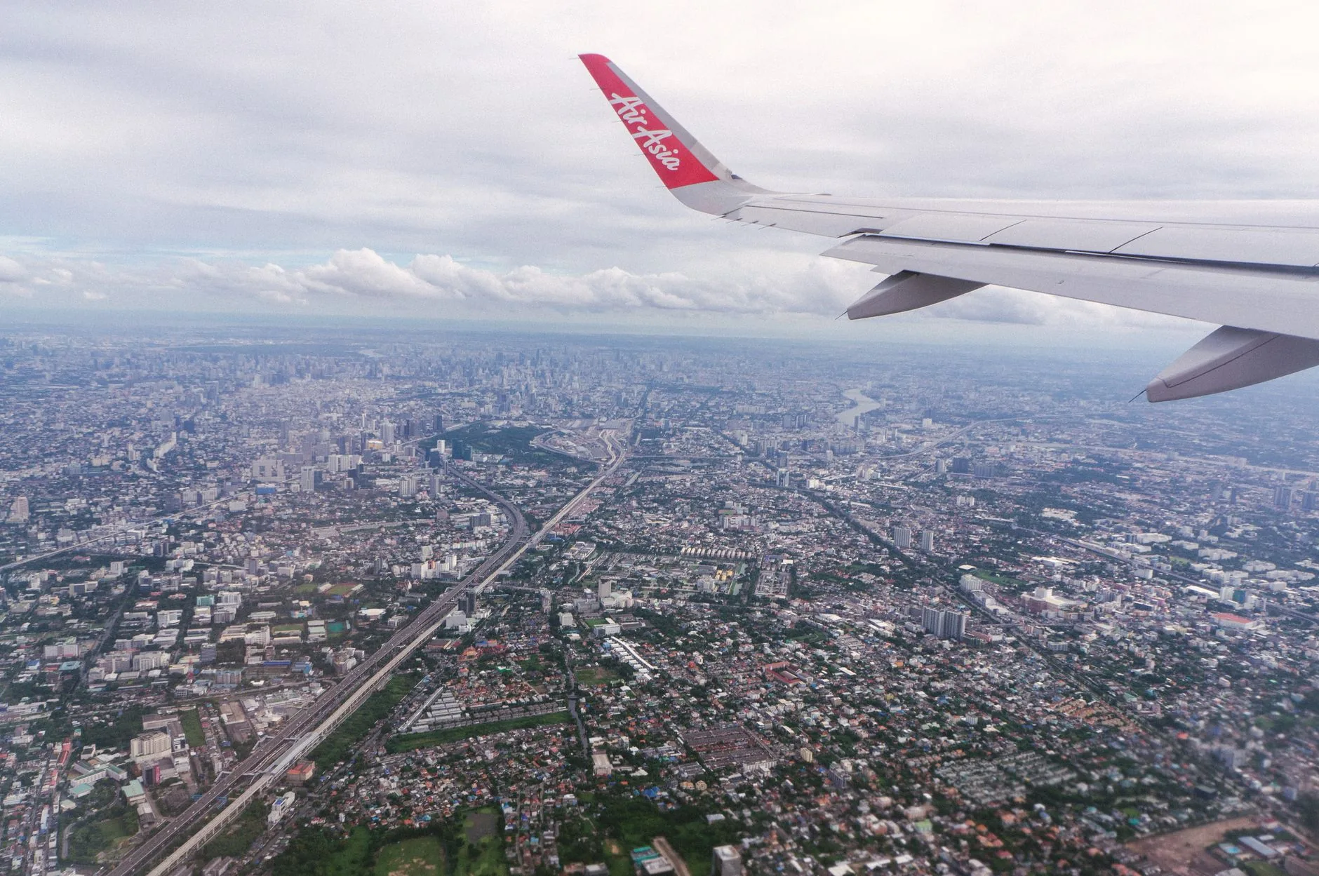 Scenic aerial view of Bangkok cityscape from an airplane window at daytime, showcasing urban sprawl.