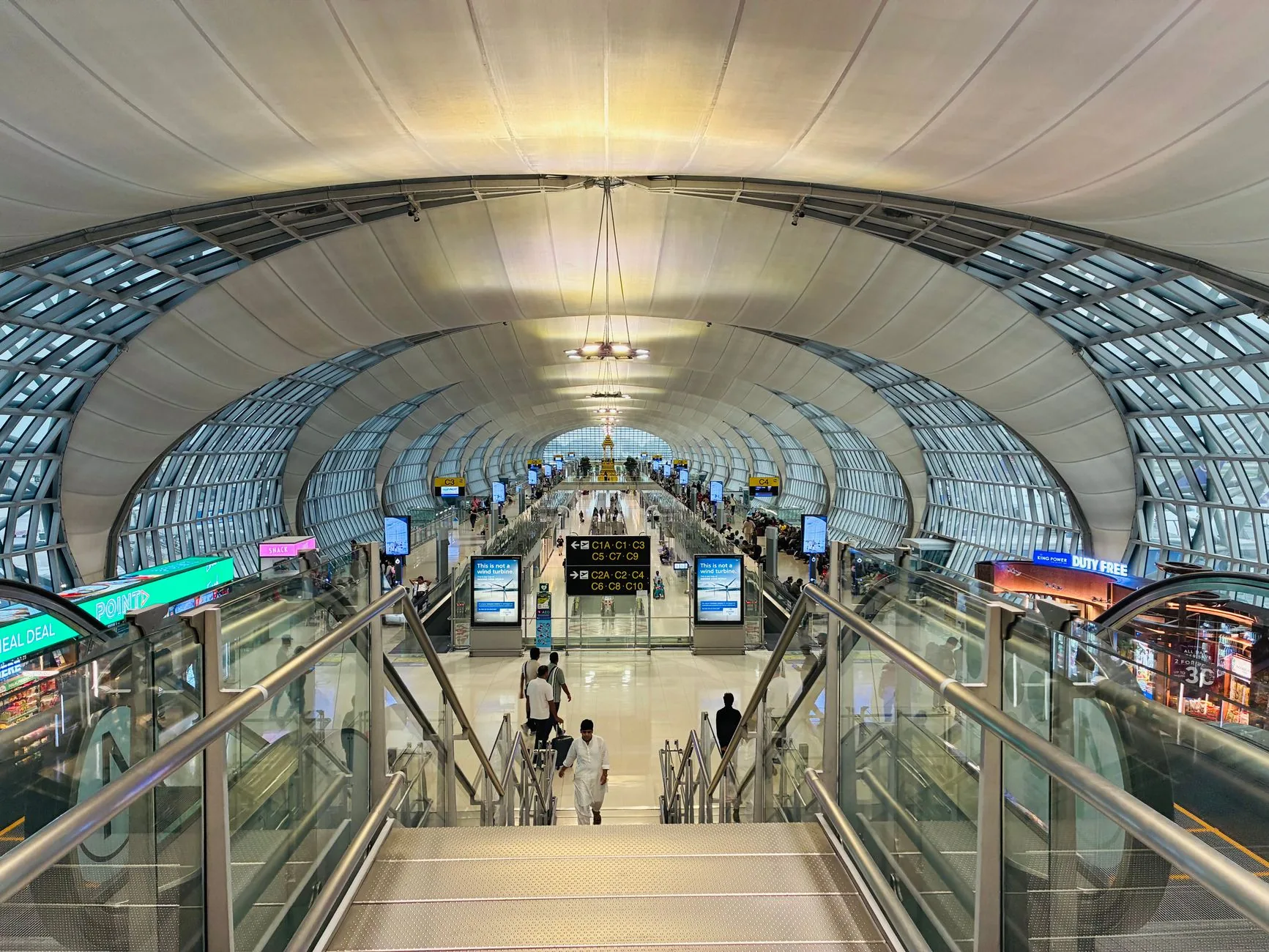 Futuristic architecture of Suvarnabhumi Airport, Bangkok, bustling with travelers.