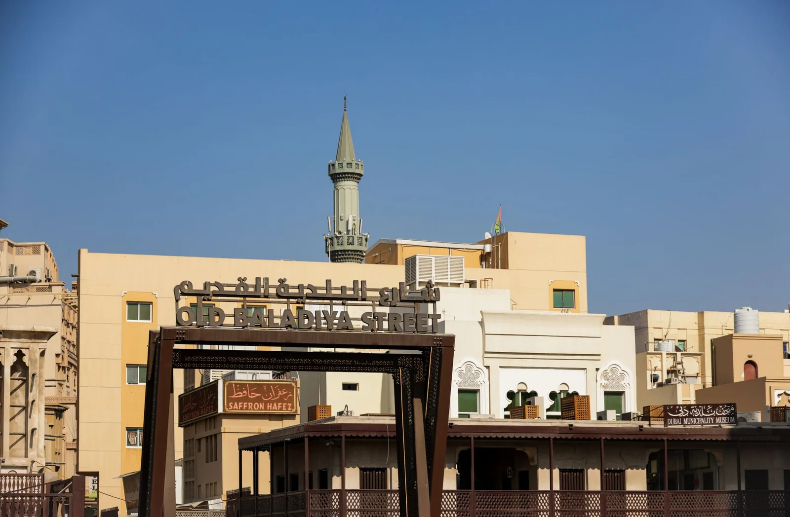 A scenic view of Old Baladiya Street featuring traditional architecture and a minaret in the background.