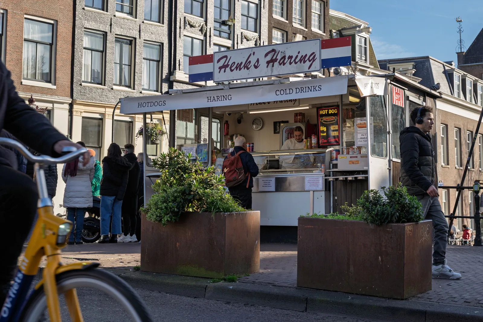 A popular food stall in Amsterdam serves traditional Dutch herring and hot dogs.