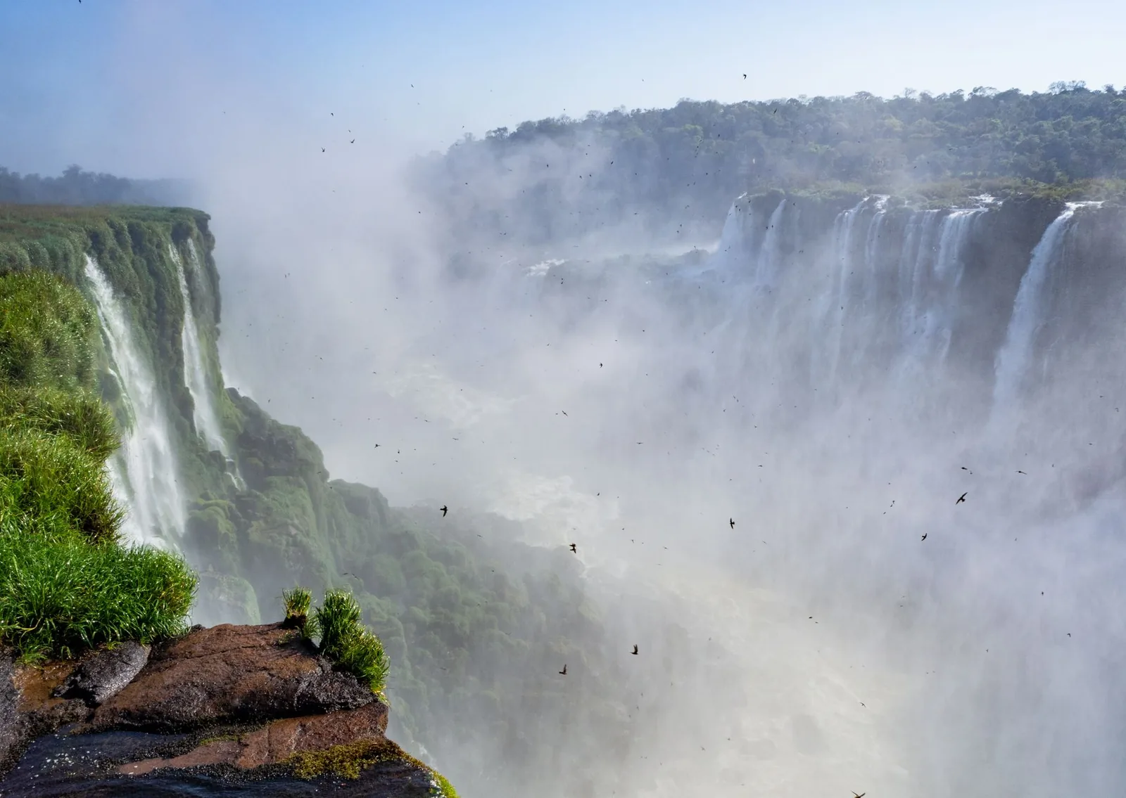 Breathtaking view of Iguazu Falls with mist rising, lush vegetation, and stunning cliffs.