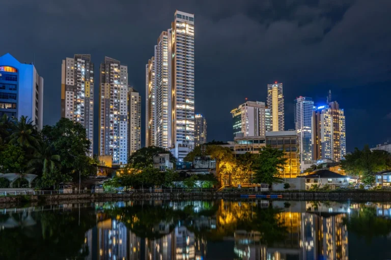 A stunning view of Colombo's skyline at night reflecting on Beira Lake, highlighting urban architecture.
