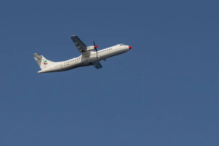A passenger airplane flying against a crisp blue sky near Cinisi, Sicily, Italy.