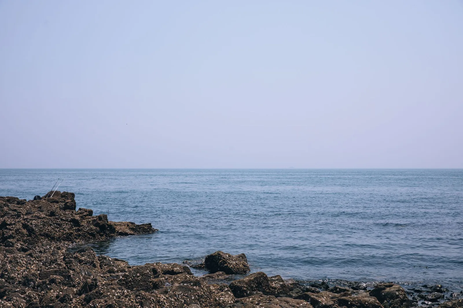 Serene rocky coastline in Dalian, China under a clear summer sky, perfect for relaxation.