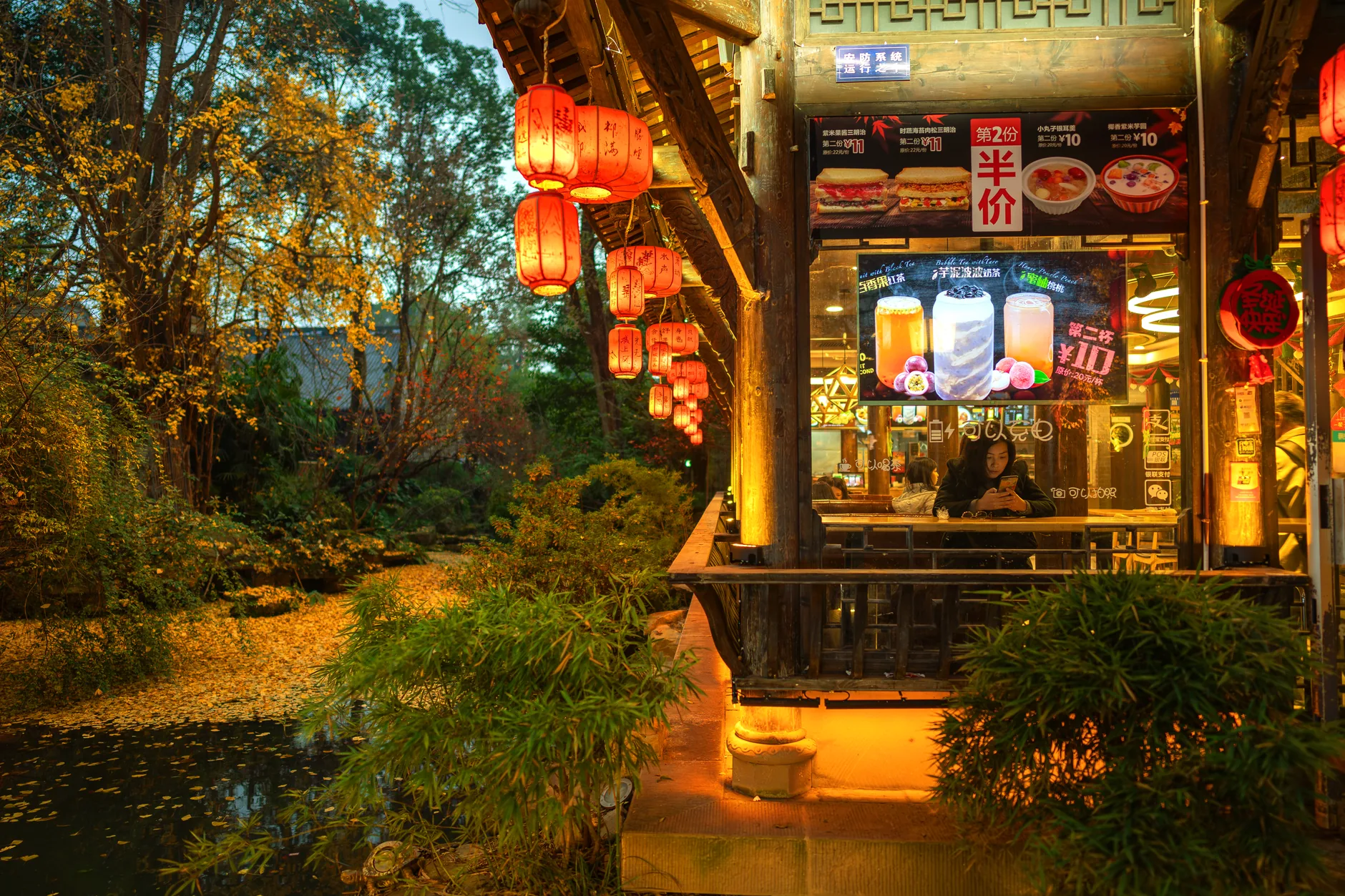 A cozy Chinese restaurant by the river with red lanterns glowing warmly at night in Chengdu, China.