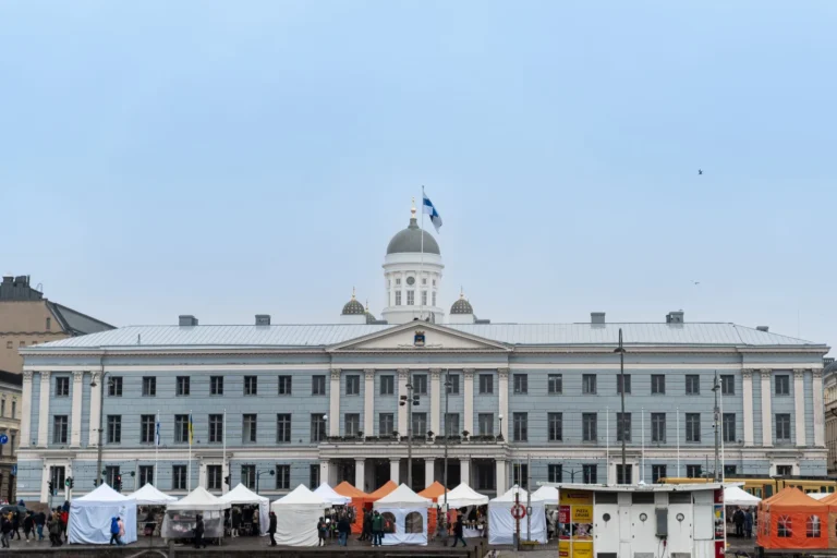 Elegant Helsinki City Hall facade with bustling market stalls below, Finland's architectural gem.