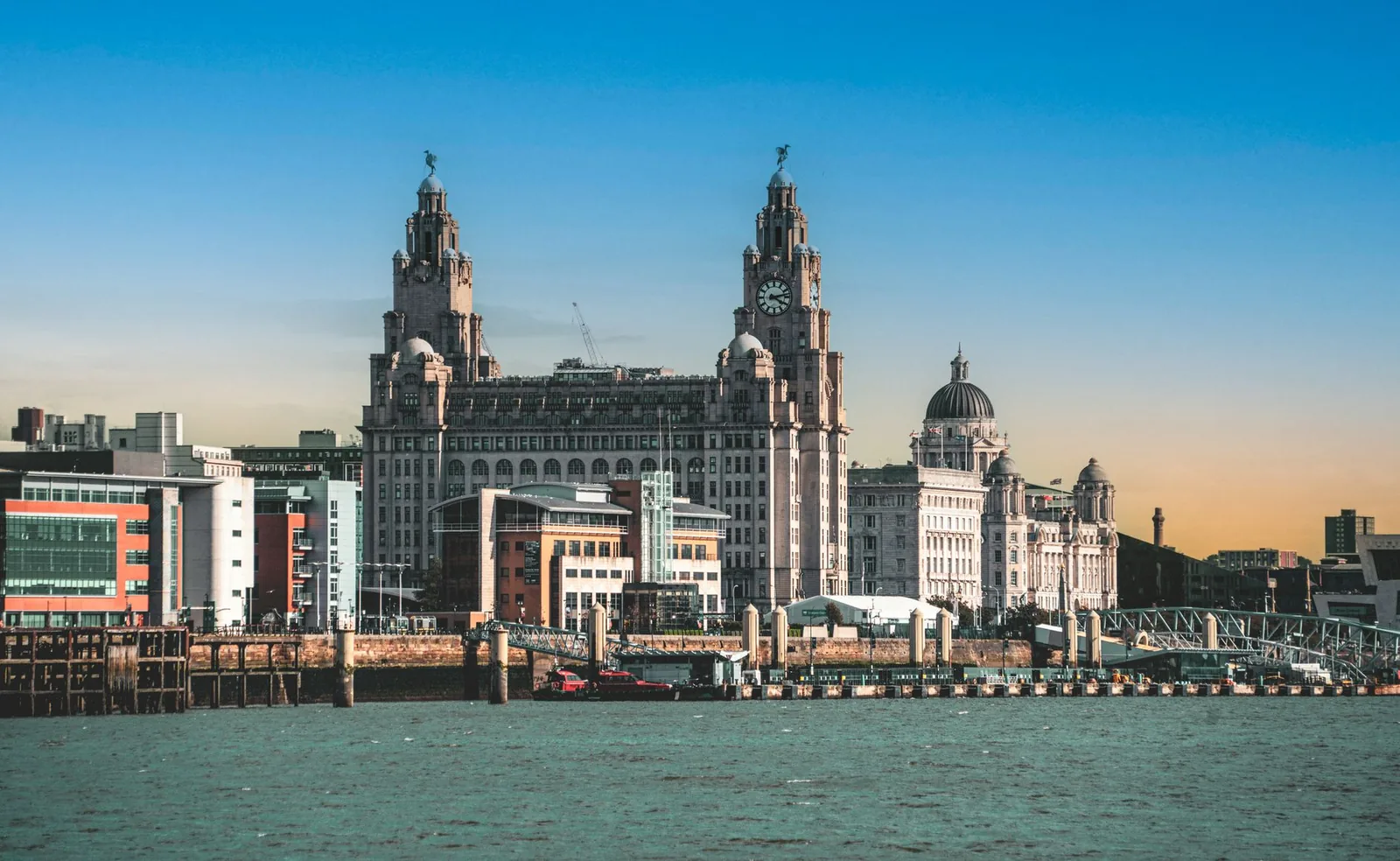 View of the historic Liver Building and waterfront in Liverpool, England at sunset.