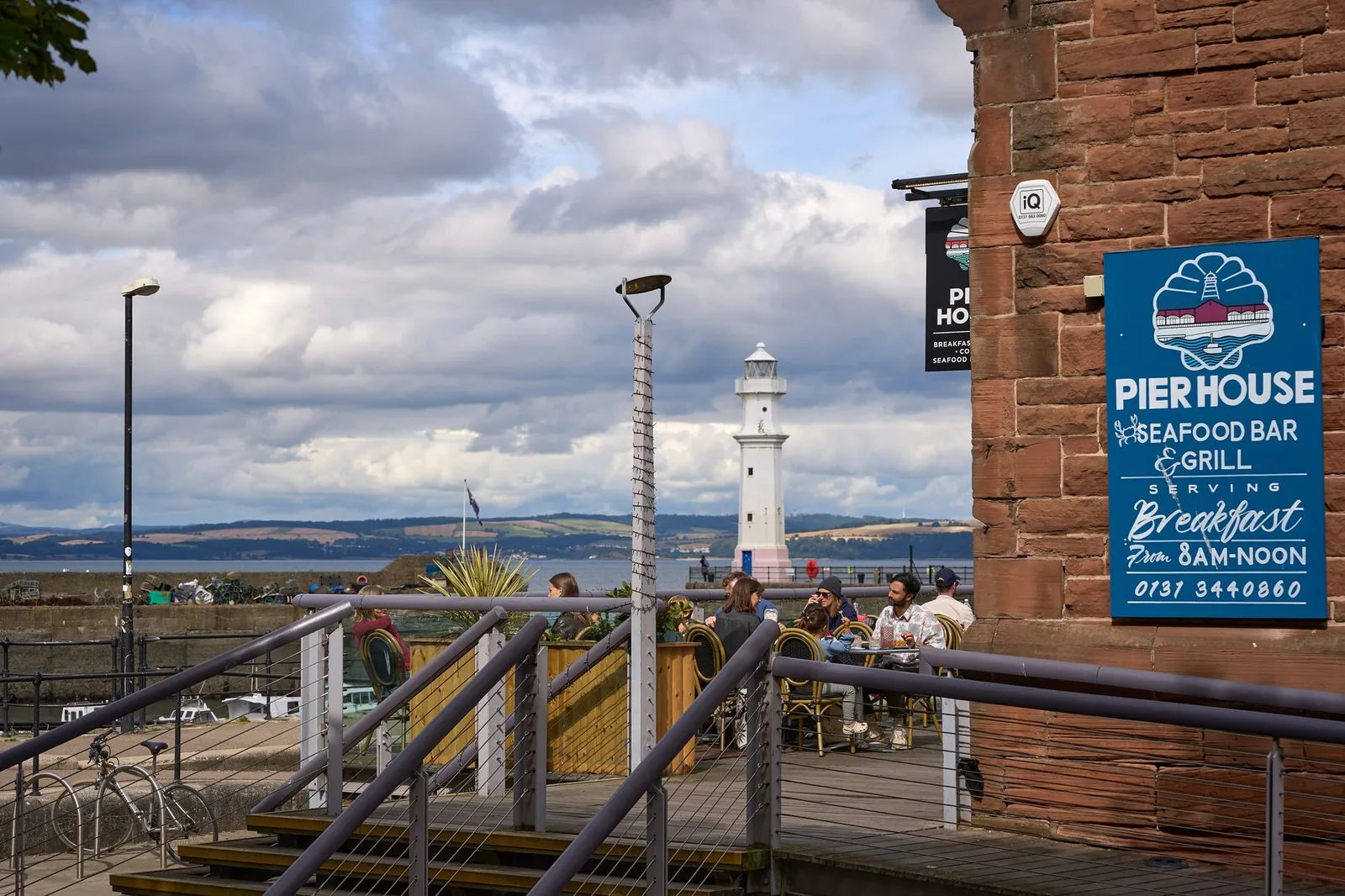 Outdoor dining at Pier House Seafood Bar with a scenic view of a lighthouse.