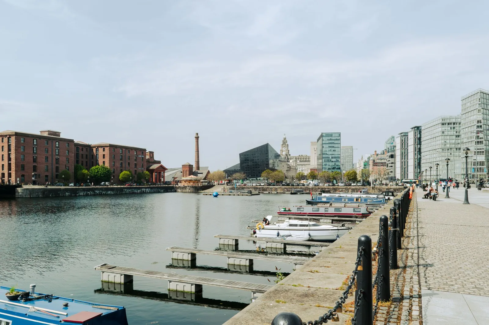 A serene view of Liverpool's waterfront with docked boats and iconic city architecture.