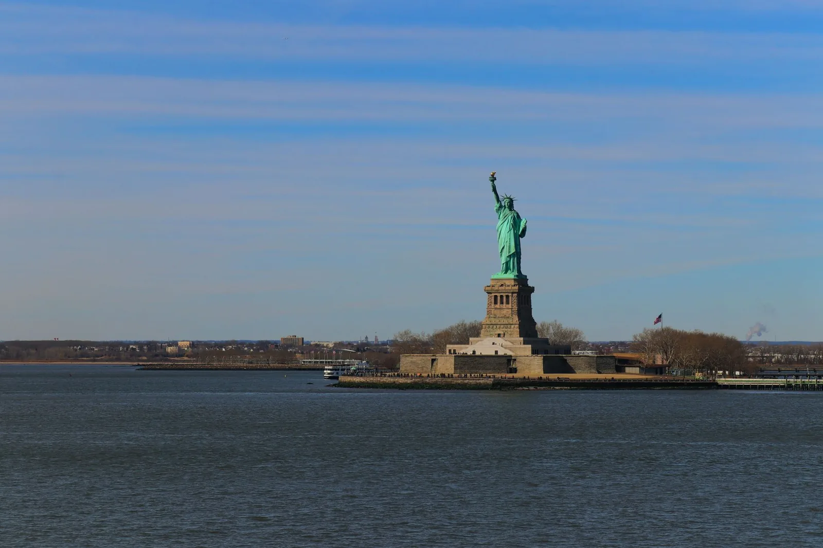 Distant view of the Statue of Liberty against a blue sky in New York City, USA.