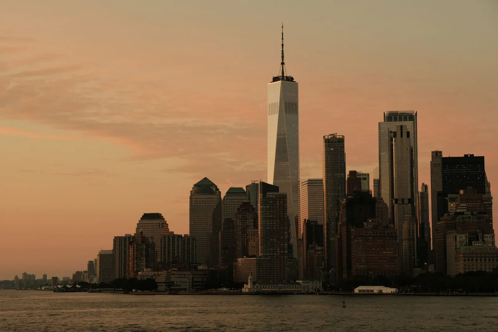 Dramatic sunset view of Lower Manhattan skyline featuring One World Trade Center in New York City.