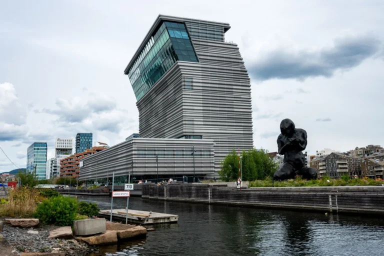 Contemporary architecture with striking statue in Oslo, featuring the Munch Museum and waterfront view.