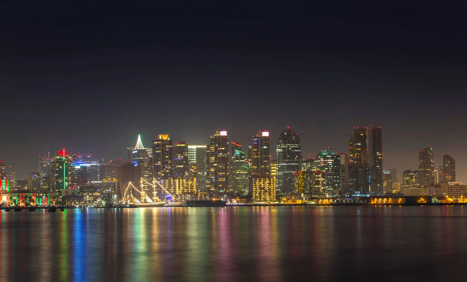 A serene night view of San Diego's illuminated skyline reflecting on calm water.